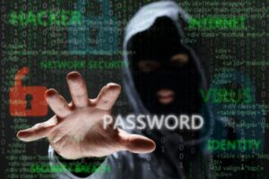 MASKED AND HOODED CYBER CRIMINAL REACHING FOR PASSWORD AND SENSITIVE INFORMATION